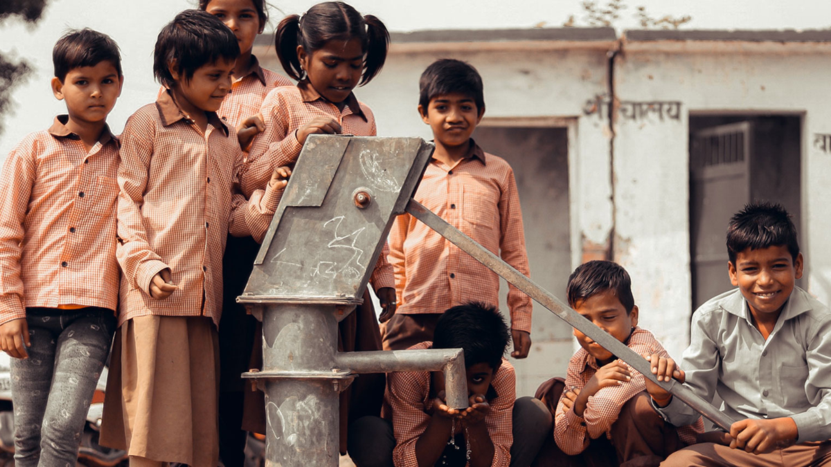 Children gathering around a community water pump